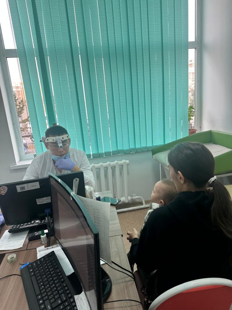 Врач принимает маму с ребёнком в кабинете поликлиники