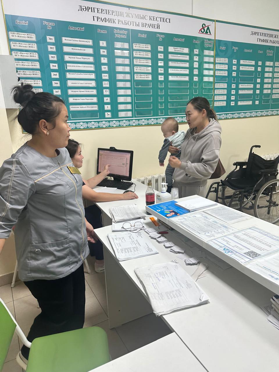 Пациентка с ребёнком на приёме у регистраторов поликлиники