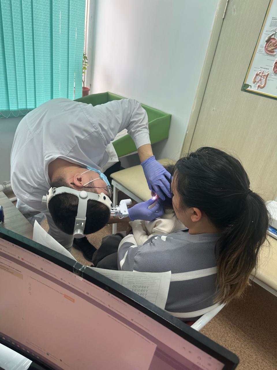 Врач проводит осмотр уха ребёнка в поликлинике