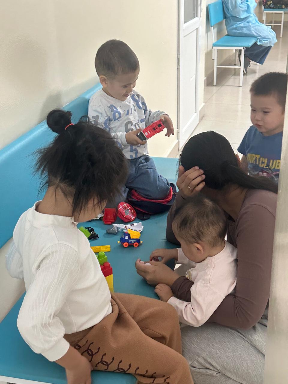 Дети играют с игрушками в холле поликлиники вместе с мамой